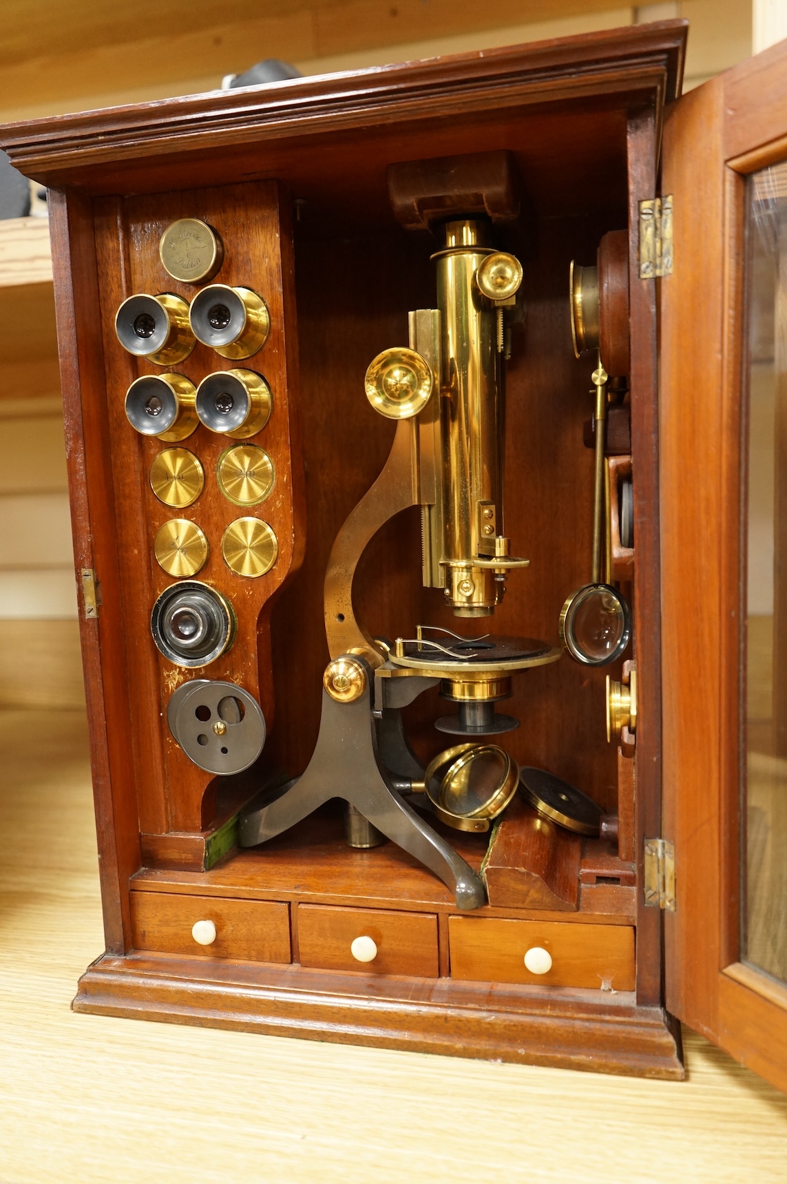 A Victorian binocular brass microscope, unsigned, in a fitted, glass fronted case with a good selection of alternative lenses and accessories, all in fitted compartments, plus three integral drawers to hold microscope sl